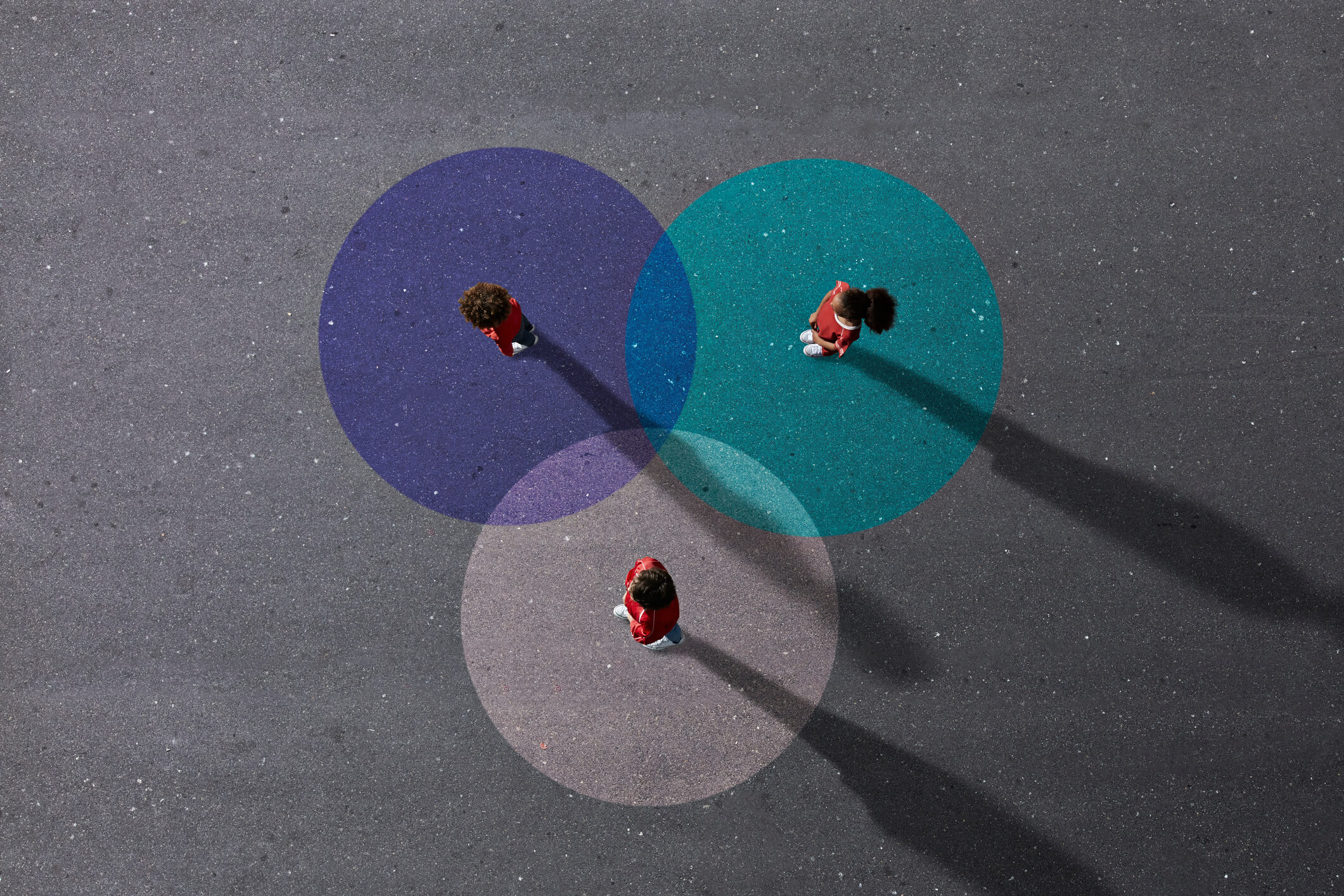 Group of children photographed from above on various painted tarmac surface at sunset