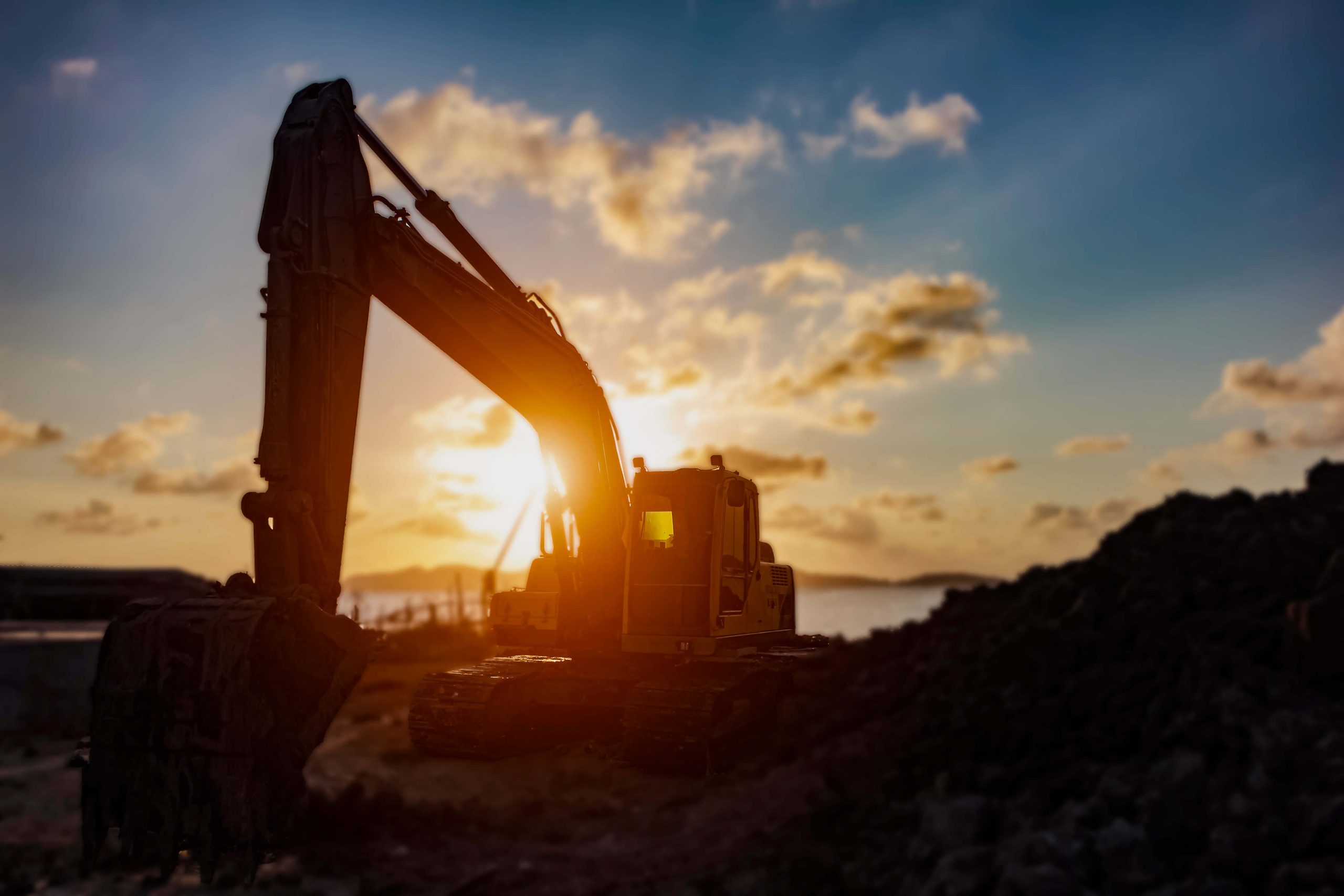 silhouette of a large construction excavator in front of an evening sky